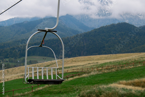 Ski Lift snowy mountain autumn forest with chair lift At The Ski Resort in Zakopane Poland. Holidays Vacation sport and outdoor activities tourism cable car empty seat grass field in green forest on photo