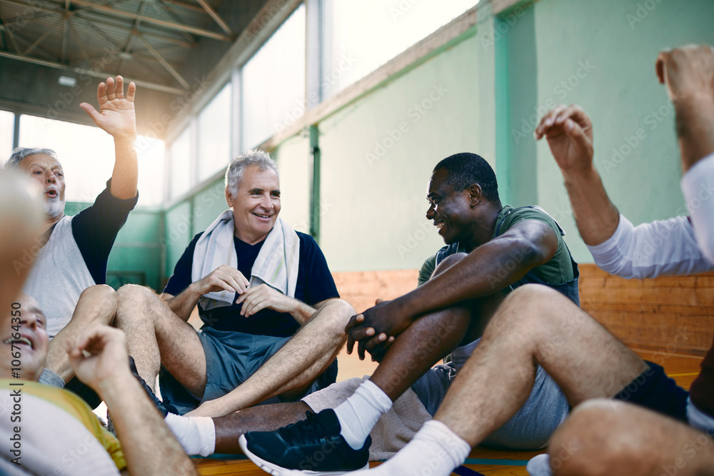 Fototapeta premium Senior men taking a break from playing basketball in an indoor gym