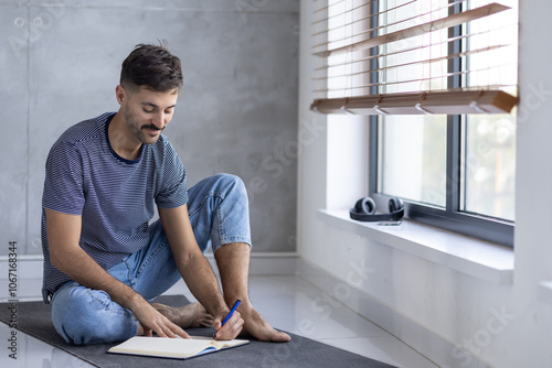 Young Man Writing Notes While Relaxing by a Window