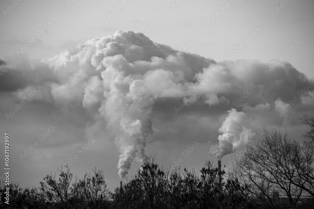 A black and white photo of a large cloud of smoke rising from a factory A black and white photo of a large cloud of smoke rising from a factory