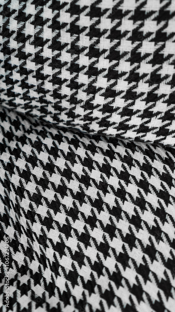 A close-up of a houndstooth pattern fabric in black and white. The intricate pattern creates a visually appealing texture and adds a touch of classic elegance to any design... A close-up of a houndstooth pattern fabric in black and white. The intricate pattern creates a visually appealing texture and adds a touch of classic elegance to any design...
