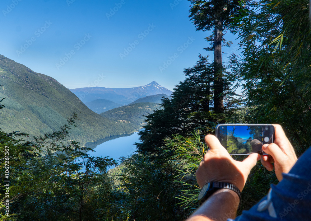 A man capturing the stunning landscape of Huerquehue National Park in southern Chile, with lush forests and mountains as a breathtaking natural backdrop.