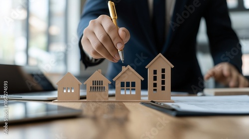 Businessman Planning Real Estate Investment with Model Houses on Office Desk.