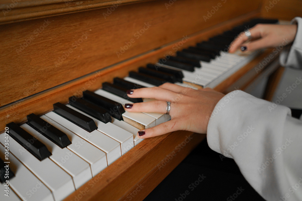 Fototapeta premium A woman with curly hair sits at a piano, enjoying the music she creates in a well-lit living room featuring cozy furniture.