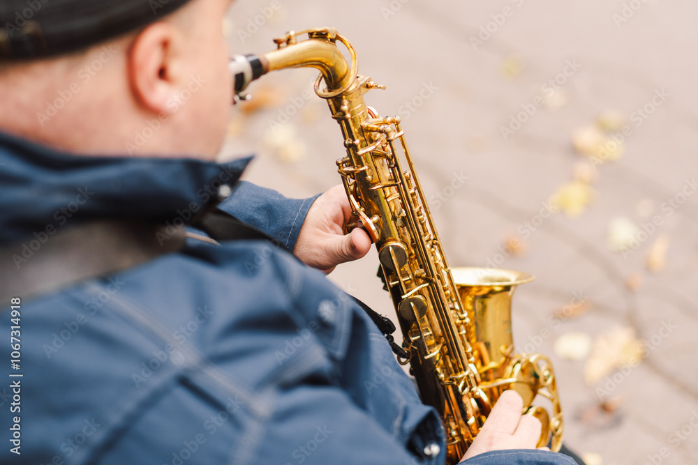 Naklejka premium A saxophonist performs in a serene park during autumn while seated on a bench surrounded by fallen leaves