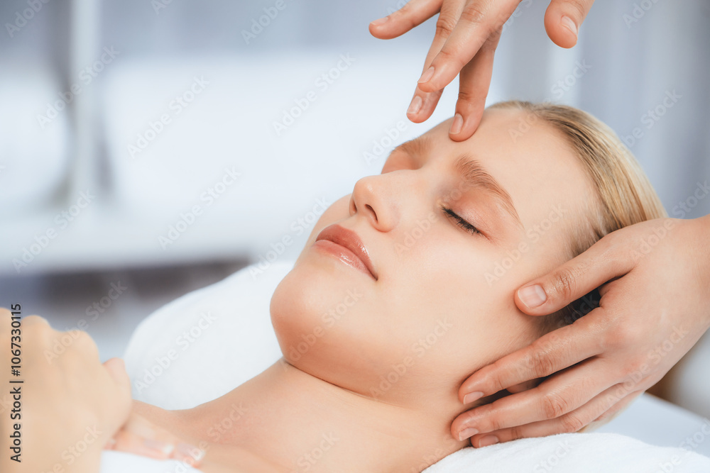 Fototapeta premium Caucasian woman enjoying relaxing anti-stress head massage and pampering facial beauty skin recreation leisure in dayspa modern light ambient at luxury resort or hotel spa salon. Quiescent