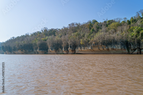 Limestone cliffs with unique erosion patterns and lush vegetation. Canoe ride along the yellow river water. Manambolo River, Madagascar. photo