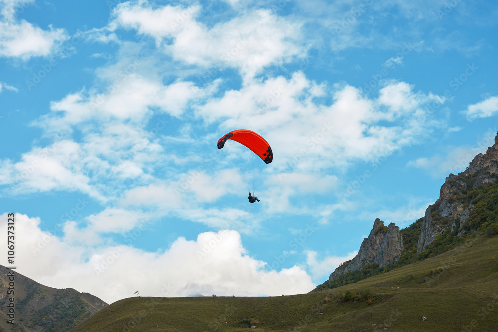 A lone paraglider in goraz against a cloudy sky towards the cliffs. Copy space. A lone paraglider in goraz against a cloudy sky towards the cliffs. Copy space.