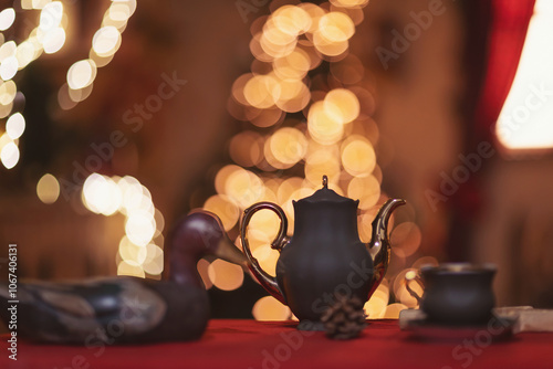 a beautiful setting of the New Year's table in red, against the background of a decorated Christmas tree. Christmas decorations. Christmas tree branches, teapot and cups on the table.