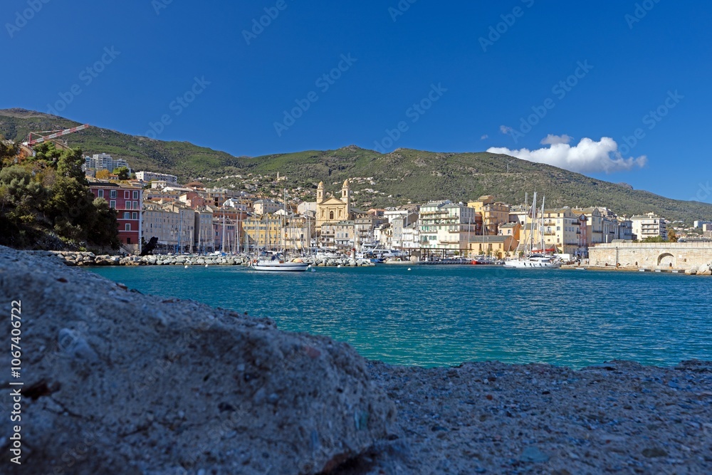 Fototapeta premium Scenic view of Bastia harbor and historic promenade with colorful buildings under a clear blue sky