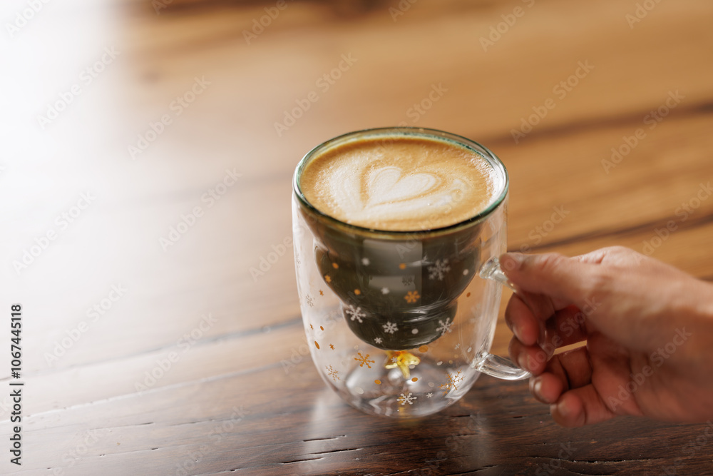 Hands of unrecognizable woman in red sweater sitting at table enjoying specialty coffee in cafe with Christmas mug with star drawings.