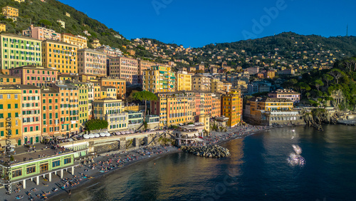 Camogli, a charming fishing village on Italy's Ligurian coast, captured from the air at sunset, reveals its colorful houses and historic harbor bathed in a warm, golden light photo