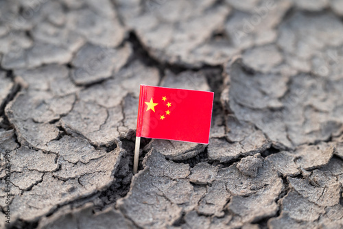 Flag of China in dry cracked ground. Concept of drought in China, hot rainless weather