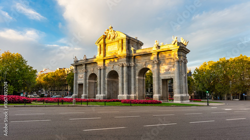 Alcala Gate seen at sunrise with the sun's rays coming through the trees, Madrid, Spain
