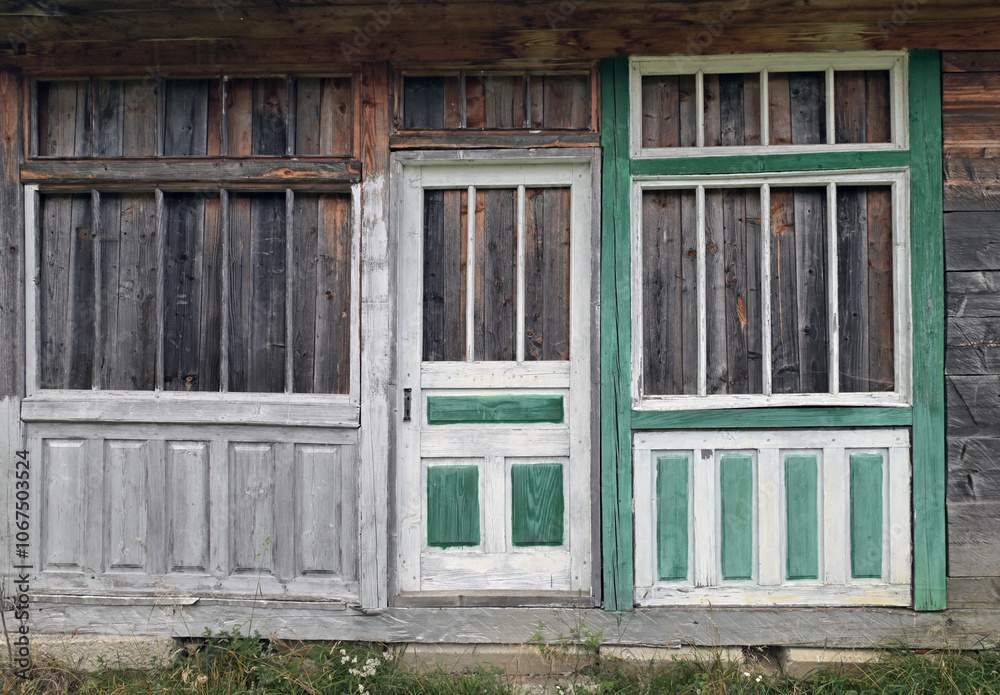 Fragment of the front wall of an abandoned wooden house with a boarded-up window and door. Fragment of the front wall of an abandoned wooden house with a boarded-up window and door.