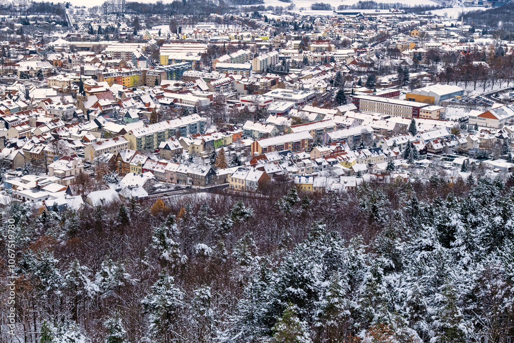 A snowy landscape with a town in the distance. The sky is cloudy and the snow is covering the ground. Germany.