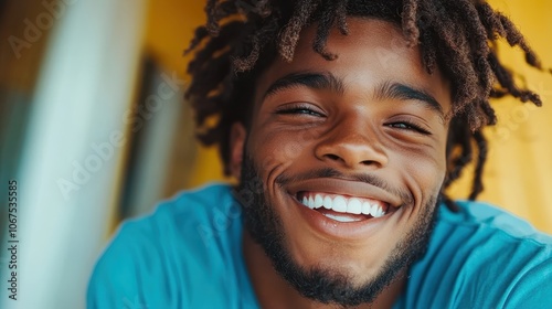 A close-up view of a young man with curly hair, laughing joyfully against a vivid yellow background, capturing a moment of pure delight and contentment. photo