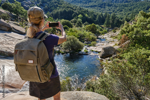 Woman with backpack taking a photo of the Carcha Verde in La Pedriza. photo