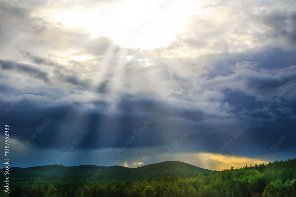 Rays of sun from behind clouds over forest and mountains Rays of sun from behind clouds over forest and mountains