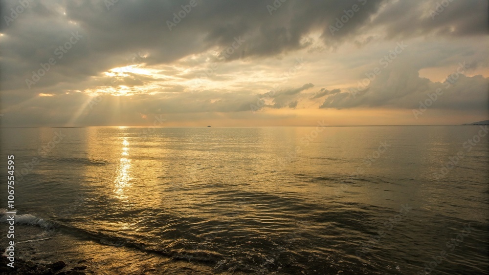 Obraz premium Soft golden light on a serene sea surface, sunlit water, soft light, peaceful atmosphere, beach at sunset