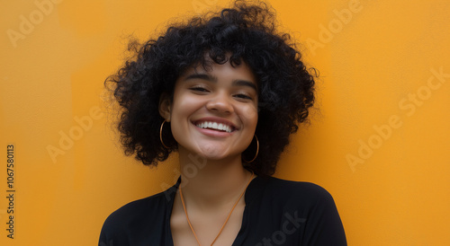 Jovem mulher com cabelos cacheados sorrindo contra uma parede laranja