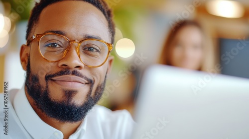 A close-up of a smiling man wearing glasses, set against a warm indoor background, reflecting leisure and positivity in modern life through his expression and setting.