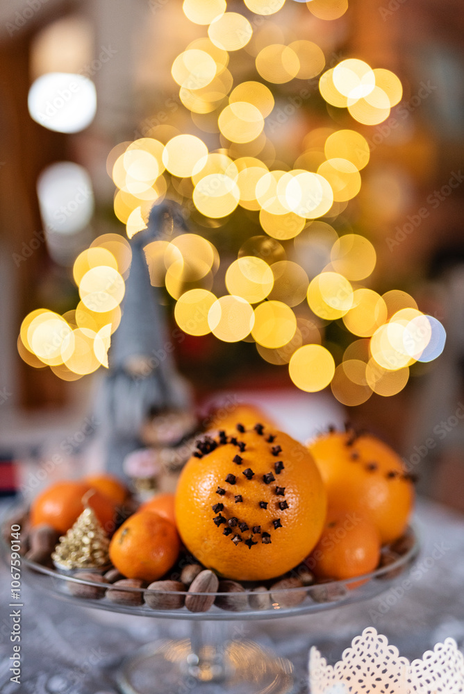 Christmas still life with orange and nuts on a plate on christmas table with christmas lights on a christmas tree in background. Decoration and bokeh in december in holidays.