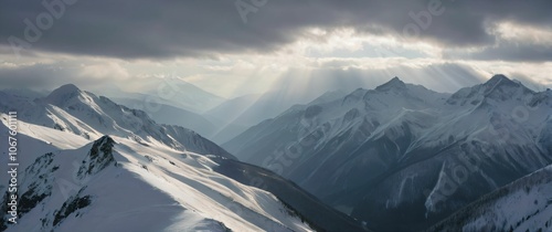 Dramatic landscape of snowcapped peaks during winter sunlight breaking through thick clouds to illuminate the valley photo