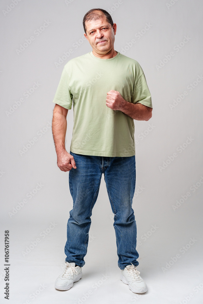 A middle-aged man stands confidently in casual attire against a neutral background A middle-aged man stands confidently in casual attire against a neutral background