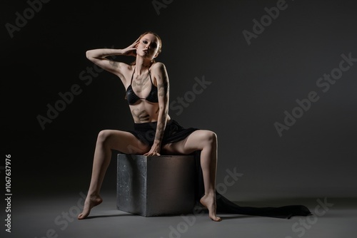 A fashion model poses dramatically on a cube in an artistic studio setting photo