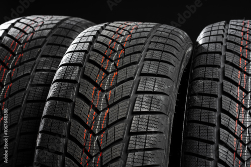 Close up of winter car tires showing tread pattern on black background