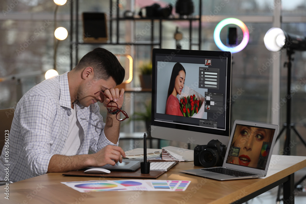 Tired retoucher at table with modern computer in office