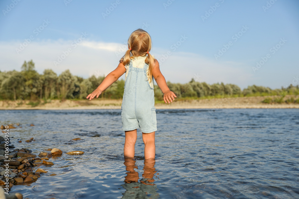 Cute little girl spending time on river. Child enjoying beautiful nature Cute little girl spending time on river. Child enjoying beautiful nature