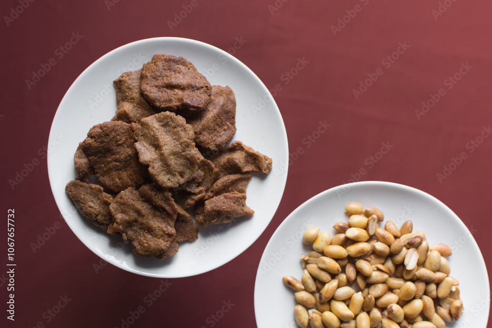 Overhead view of kuli-kuli and roasted peanuts on a white plate, top view of nigerian groundnut cakes and groundnuts on a plate
