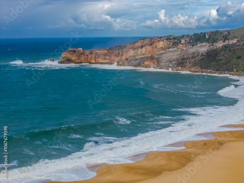 Aerial drone view of Portugal coastal town Nazare with lighthouse on a cliff on the coast of Atlantic ocean with big waves. Panoramic view of Nazare