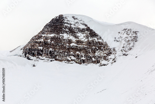 dramatic winter landscape with a rugged mountain peak stands tall, covered in snow and ice