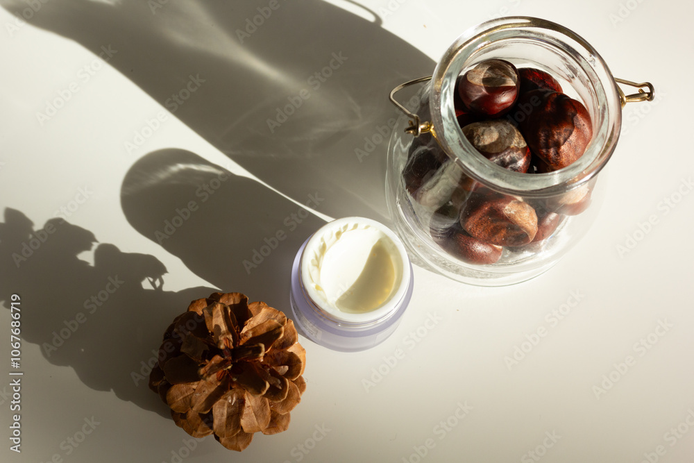 Concept of autumn skincare. Closeup of a jar of moisturizer and chestnuts.