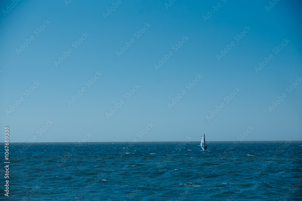 A sailboat is floating in the ocean on a clear day A sailboat is floating in the ocean on a clear day