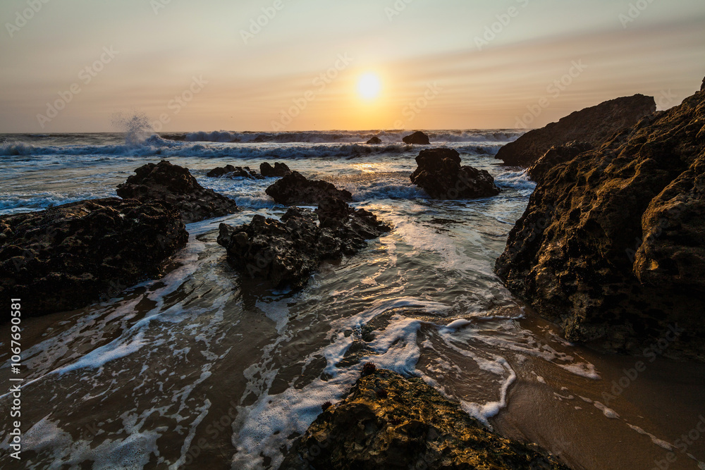 coastal sunset scene, waves rush in from the open sea, filling the space between the dark, rugged rocks coastal sunset scene, waves rush in from the open sea, filling the space between the dark, rugged rocks