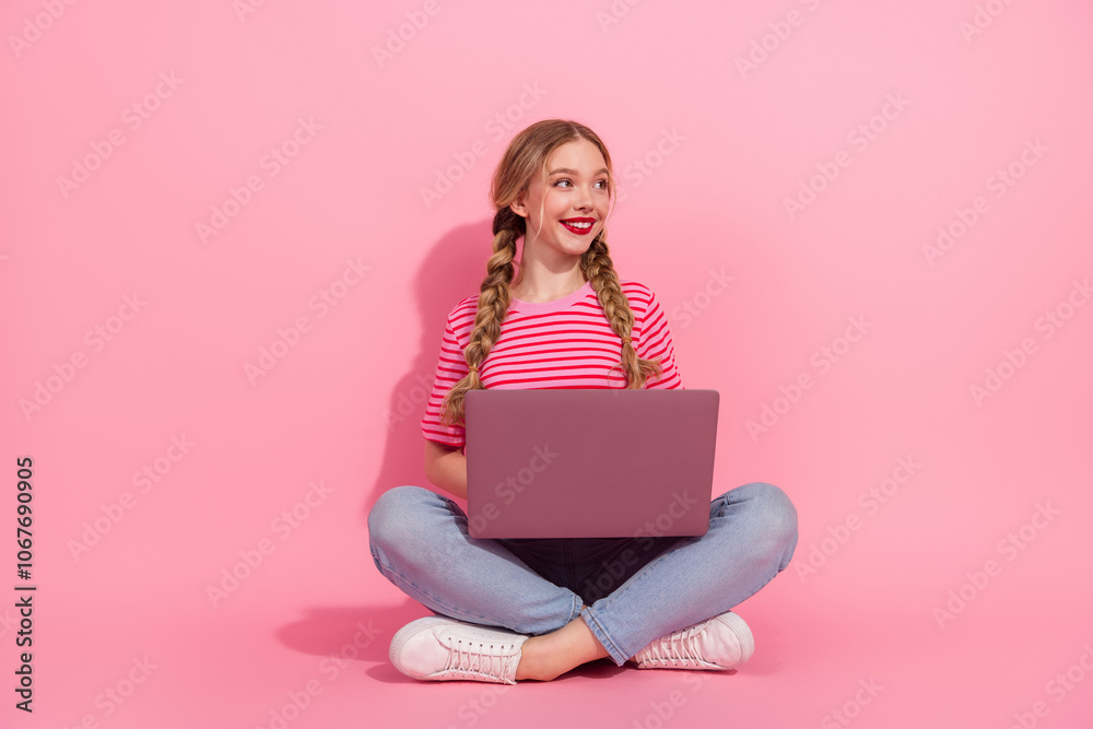Young blonde woman in striped t-shirt with laptop on pink background Young blonde woman in striped t-shirt with laptop on pink background