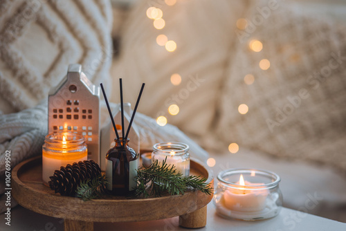 Winter home aromatherapy. Scented aroma candles, fir tree or spruce scent, decorative pine cones on wooden tray. Cozy atmosphere, relaxation, festive mood, interior decor bedroom, living room photo