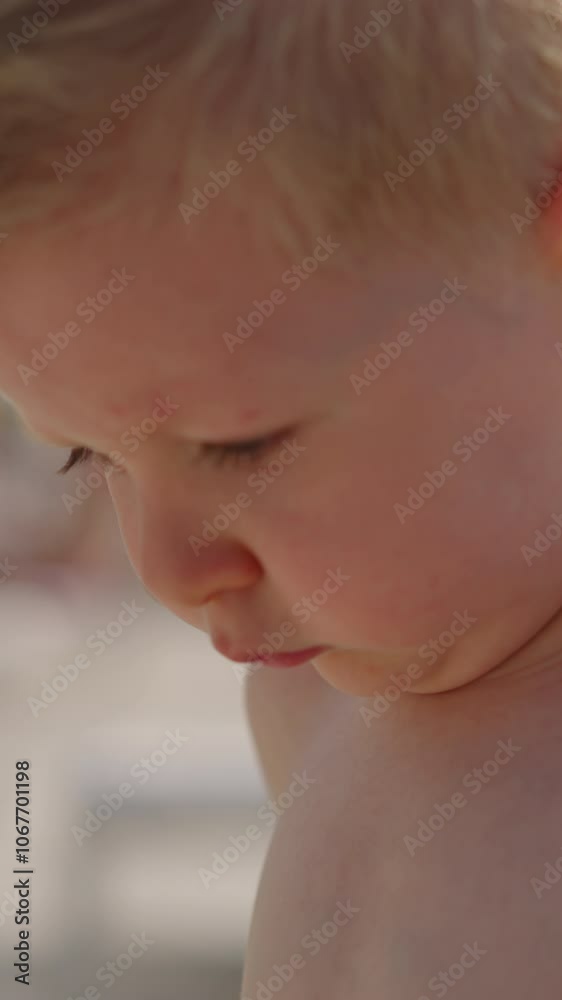 Pensive little child boy with bare shoulders stands on public beach at contemporary marine resort on warm summer day closeup slow motion Pensive little child boy with bare shoulders stands on public beach at contemporary marine resort on warm summer day closeup slow motion