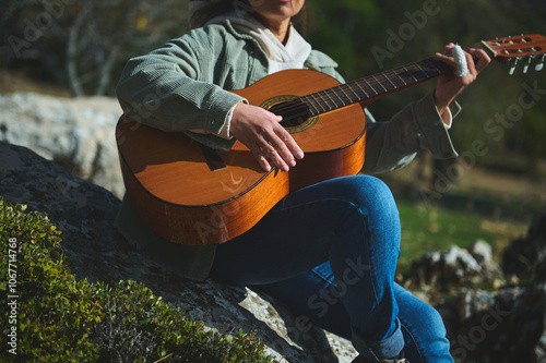 Person playing acoustic guitar outdoors on a sunny day photo