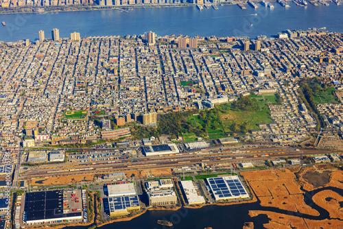 Aerial view of urban area in New Jersey near the Hudson River, featuring buildings, parks, and industrial zones.