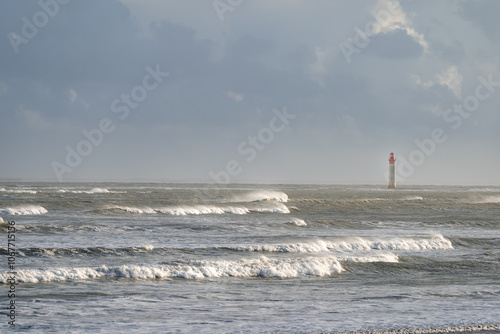 Chauveau lighthouse in the sea during windstorm with waves on a blue sky