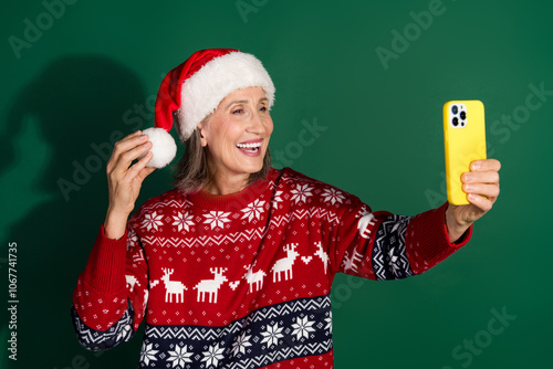 Photo of cheerful holly jolly woman wear stylish clothes hold device take selfie isolated on green color background photo