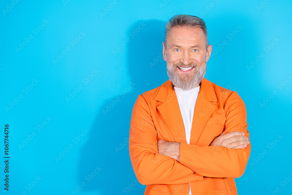 Photo of trendy eccentric man crossed arms empty space wear orange suit isolated on blue color background Photo of trendy eccentric man crossed arms empty space wear orange suit isolated on blue color background