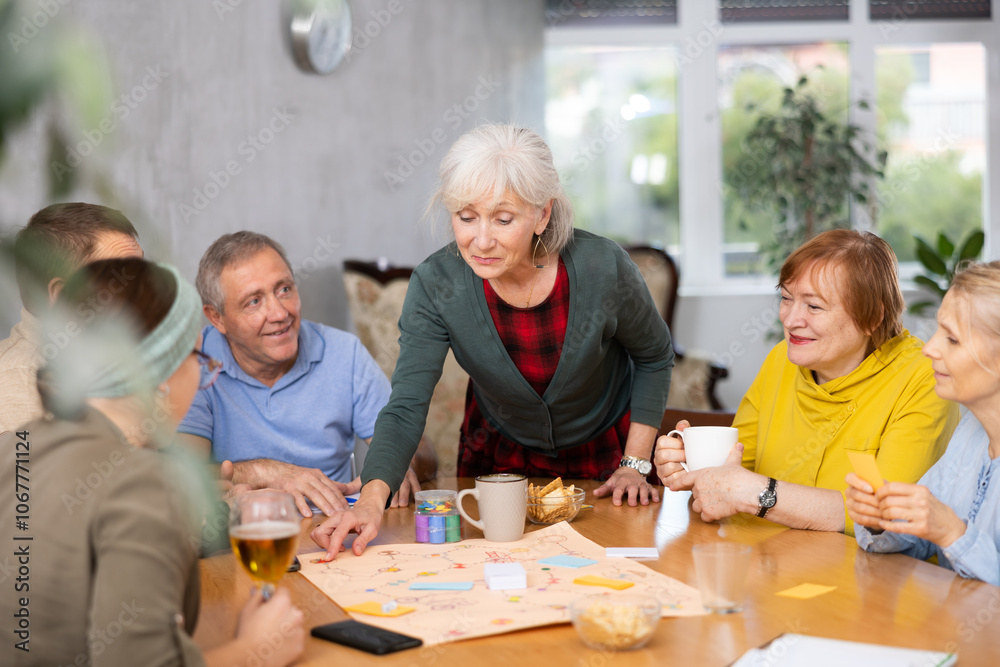 Fototapeta premium Retirees play board games and drink tea with cookies