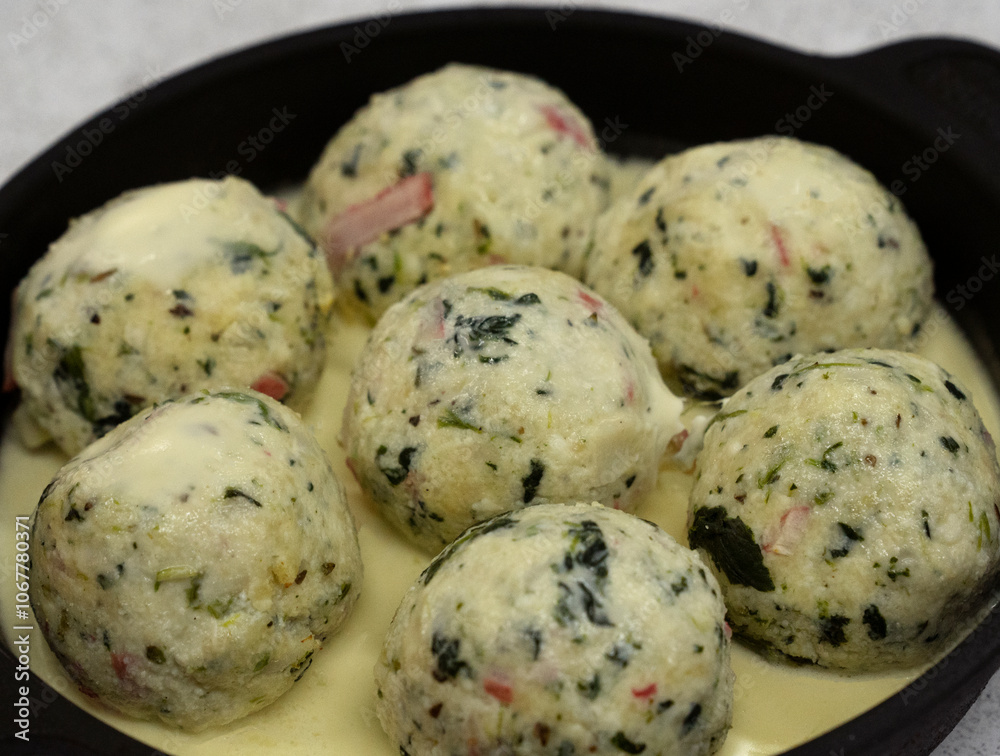 Italian pasta. Closeup view of ricotta, spinach and cheese malfatti with a creamy sauce in a black rustic dish on the table Italian pasta. Closeup view of ricotta, spinach and cheese malfatti with a creamy sauce in a black rustic dish on the table