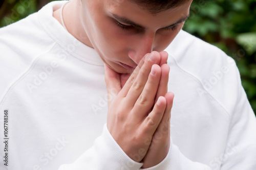 Hope for the future. Young handsome man in the public park is praying to God. Concept for faith, spirituality and religion.